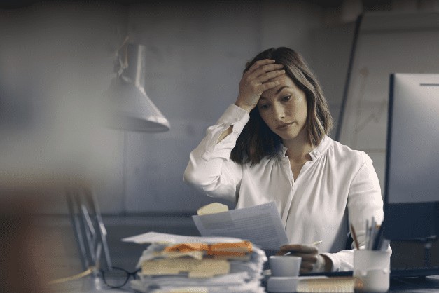 stressed woman looking at a stack of papers